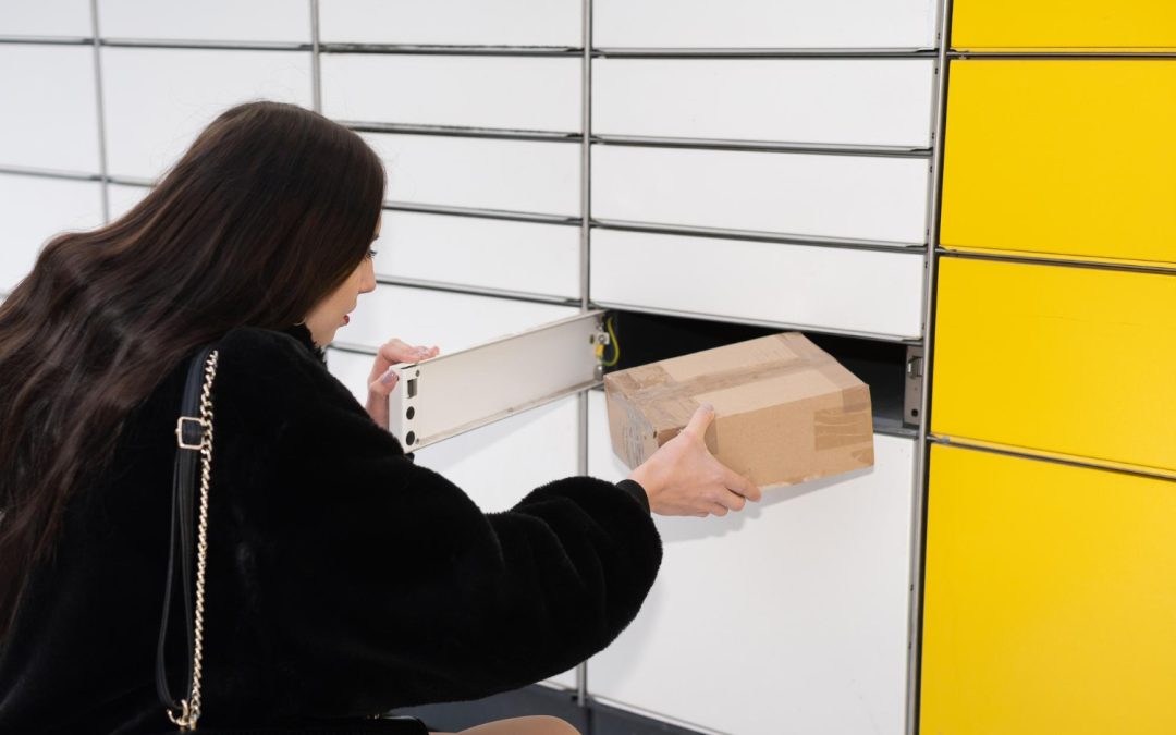 A woman places a cardboard package into a locker with white and yellow compartments.